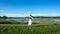 Beautiful young spiritual blonde woman long hair dancing and spinning in a field next to a lake white skirt