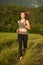 Beautiful young sporty woman workout in nature runs on a path on meadow