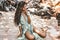 Beautiful young stylish woman sitting on sand on the beach