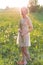 Beautiful young sweet girl in a white dress with hair on the head oblique walks in a field at sunset