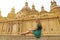 Beautiful young tourist woman sitting on wall looking at stunning Basilica of Our Lady of the Pillar in Zaragoza, Spain