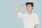 Beautiful young US Navy officer saluting over light blue background