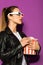beautiful young woman in 3d glasses holding box of popcorn and looking away