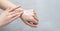 Beautiful young woman applying hand cream on gray background. Skincare cream on a female wrist