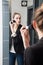 Beautiful young woman applying her blush or face powder before mirror