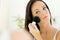 Beautiful young woman applying Make-up with Cosmetics Brush