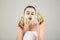 Beautiful young woman with avocado facial mask on light background