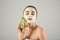 Beautiful young woman with avocado facial mask on light background