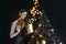 Beautiful young woman on the background of a Christmas tree. A New Year& x27;s gift. Black background.a magical gift