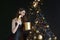 Beautiful young woman on the background of a Christmas tree. A New Year& x27;s gift. Black background.a magical gift