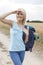 Beautiful young woman with backpack shielding eyes while hiking at field