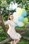 Beautiful young woman with balloons sitting on tree