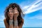 Beautiful young woman on the beach background cover her face wit