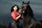 Beautiful young woman with a black horse