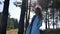 Beautiful young woman in blue coat standing in forest in windy weather autumn Sunny day