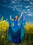 Beautiful young woman in blue dress posing outdoor with cloudy dramatic sky in background