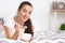 Beautiful young woman with bowl of tasty oatmeal having breakfast in bedroom