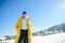 Beautiful young woman in a bright yellow down-padded coat poses for the camera