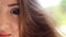 Beautiful young woman with brown hair smiling on a windy day. Portrait half face closeup.