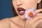 Beautiful young woman with brown lipstick and flower on color background, closeup