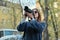 Beautiful young woman with camera in city. Tourist girl traveling and photographing, spring city street background