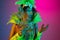 Beautiful young woman in carnival and masquerade costume on gradient studio background in neon light