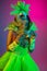 Beautiful young woman in carnival and masquerade costume on gradient studio background in neon light