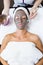 Beautiful young woman with clay facial mask in beauty spa. Detox
