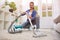 Beautiful young woman cleaning with vacuum cleaner