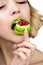 Beautiful young woman with colored rainbow eyelashes and bright makeup eats macaroon sweetie, close-up