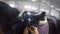 Beautiful young woman cowgirl standing and putting saddle on horse gopro. Close-up of a young girl carrying saddle to