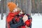 Beautiful young woman is cuddling little dog wrapped in red checkered plaid on a walk in winter forest