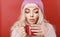Beautiful young woman with cup of hot drink on red background.