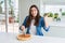 Beautiful young woman cutting a tasty pizza slice using a cutter very happy and excited, winner expression celebrating victory