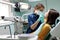 The beautiful young woman is at the dentist. She sits in the dentist`s chair and the dentist carefully examines the patient`s