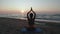 Beautiful Young Woman Doing Sitting Yoga on the Beach while Watching the Sunset.