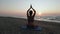 Beautiful Young Woman Doing Sitting Yoga on the Beach while Watching the Sunset.