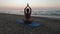 Beautiful Young Woman Doing Sitting Yoga on the Beach while Watching the Sunset.