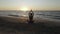 Beautiful young woman doing sitting yoga on the beach while watching the sunset.