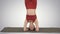 Beautiful young woman doing yoga exercise variation of supported headstand, garuda salamba sirsasana with crossed legs