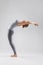 Beautiful young woman doing yoga on a gray studio background