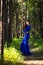 Beautiful, young woman dressed in a blue dress, on a background of a pine forest.