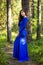 Beautiful, young woman dressed in a blue dress, on a background of a pine forest.