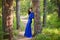 Beautiful, young woman dressed in a blue dress, on a background of a pine forest.