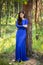 Beautiful, young woman dressed in a blue dress, on a background of a pine forest.