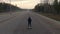 A beautiful young woman drives alone on the highway on the hoverboard towards sunset