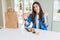 Beautiful young woman eating asian sushi from home delivery pointing and showing with thumb up to the side with happy face smiling