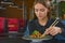 Beautiful young woman eating chinese food called Wok with chopsticks. Wok with meat and fried asparagus in a plate