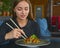 Beautiful young woman eating chinese food called Wok with chopsticks. Wok with meat and fried asparagus in a plate