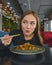 Beautiful young woman eating chinese food called Wok with chopsticks. Wok with meat and fried asparagus in a plate